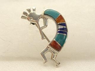 Genuine Turquoise, Blue Lapis and Spiny Oyster Shell inlaid between ribbons of  Sterling Silver. Beautiful Sterling Silver Kokopelli Brooch.  Created by Navajo Artist Calvin Begay.
