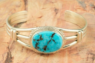 Genuine Boulder Turquoise set in Sterling Silver Bracelet. The cabochon is Boulder Turquoise, you can see the veins of Turquoise running through the host rock. The Boulder Turquoise Mine is located in northeast Nevada. It was discovered in 1970 by a Shoshone sheep herder. Production is small due to the remote location and winter weather. Boulder Turquoise is valued for both it's beauty and rarity. Every stone is unique. Created by Navajo Artist Larson Lee. Signed.