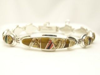 Genuine Turquoise, Spiny Oyster Shell, Sugilite and Blue Lapis inlaid between ribbons of Sterling Silver. Precision channel inlay. Designed by Navajo Artist Calvin Begay. Signed. 
