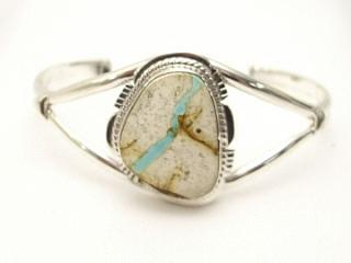 Genuine Boulder Turquoise set in Sterling Silver Bracelet. The cabochon is Boulder Turquoise, you can see the veins of Turquoise running through the host rock. The Boulder Turquoise Mine is located in northeast Nevada. It was discovered in 1970 by a Shoshone sheep herder. Production is small due to the remote location and winter weather. Boulder Turquoise is valued for both it's beauty and rarity. Every stone is unique. Created by Navajo Artist Margaret Platero.