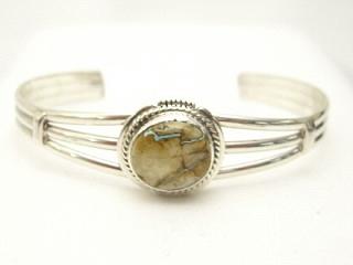 Genuine Boulder Turquoise set in Sterling Silver Bracelet. The cabochon is Boulder Turquoise, you can see the veins of Turquoise running through the host rock. The Boulder Turquoise Mine is located in northeast Nevada. It was discovered in 1970 by a Shoshone sheep herder. Production is small due to the remote location and winter weather. Boulder Turquoise is valued for both it's beauty and rarity. Every stone is unique. Created by Navajo Artist Kathy Yazzie. Signed.