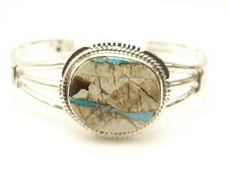 Genuine Boulder Turquoise set in heavy gauge Sterling Silver Bracelet. The cabochon is Boulder Turquoise, you can see the veins of Turquoise running through the host rock. The Boulder Turquoise Mine is located in northeast Nevada. It was discovered in 1970 by a Shoshone sheep herder. Production is small due to the remote location and winter weather. Boulder Turquoise is valued for both it's beauty and rarity. Every stone is unique. Created by Navajo Artist John Nelson. Signed.