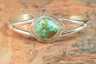 Genuine Royston Turquoise set in Sterling Silver Bracelet. The Royston Turquoise Mine was originally known as the Royal Blue Mine. It produces Turquoise that has a mixture of blues and greens in the same formation. The Royston Turquoise Mine is located in Nye County, Nevada. Created by Navajo Artist John Nelson. Signed by the artist.