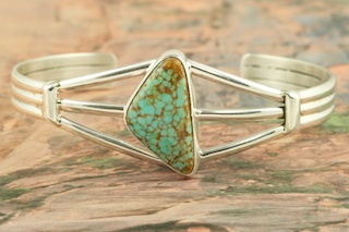 Genuine Number 8 Mine Turquoise Stone set in heavy gauge Sterling Silver Bracelet. Created by Navajo Artist Phillip Sanchez. Signed by the artist. The Number 8 mine is located in Eureka County Nevada. Since 1976 there has been no Number 8 Turquoise mined. There is however, an existing stock pile that Mr. Dowell Ward, the last owner of the Number 8 mine, had stocked away for later sorting. The Turquoise is a collector's item--because once the reserve is gone there will be no more material released onto the market. The Gold Mining Company owns the claim to the Number 8 mine and it has been swallowed up by the gold mining operations. This is some of the last Number 8 Turquoise to be had and will be a great addition to your collection.