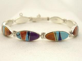 Genuine Sleeping Beauty Turquoise, Spiny Oyster Shell, Blue Lapis and Suglite inlaid between ribbons of Sterling Silver. Beautiful oval design. Designed by Navajo Artist Calvin Begay. Signed. 
