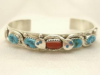 Genuine Turquoise and Coral set in Sterling Silver. Created by Zuni Artist Effie Calavaza. A signature trademark of Effie's is the snake symbol, entwined around Turquoise on Sterling Silver. Signed Effie C. Zuni. 
