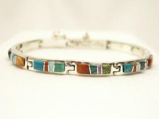 Genuine Sleeping Beauty Turquoise, Spiny Oyster Shell and Sugilite inlaid between ribbons of Sterling Silver. Beautiful bracelet Designed by Navajo Artist Calvin Begay. Signed. 
