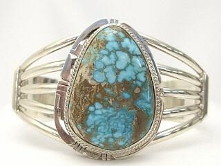 Genuine Number 8 Mine Turquoise Stone set in Sterling Silver Bracelet. Stunning Turquoise Stone. Created by Navajo Artist Phillip Sanchez. Signed. The Number 8 mine is located in Eureka County Nevada. Since 1976 there has been no Number 8 Turquoise mined. There is however, an existing stock pile that Mr. Dowell Ward, the last owner of the Number 8 mine, had stocked away for later sorting. The Turquoise is a collector's item--because once the reserve is gone there will be no more material released onto the market. The Gold Mining Company owns the claim to the Number 8 mine and it has been swallowed up by the gold mining operations. This is some of the last Number 8 Turquoise to be had and will be a great addition to your collection. 
