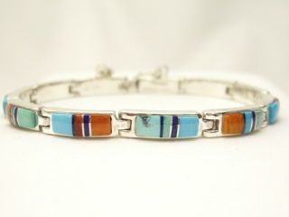 Genuine Sleeping Beauty Turquoise, Spiny Oyster Shell, Blue Lapis and Sugilite inlaid between ribbons of Sterling Silver. Stunning bracelet featuring precision channel inlay. Designed by Navajo Artist Calvin Begay. Signed