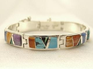 Genuine Sleeping Beauty Turquoise, Spiny Oyster Shell, Black Jade and Sugilite inlaid between ribbons of Sterling Silver. Stunning bracelet featuring precision channel inlay. Created by Navajo Artist Calvin Begay. Signed
