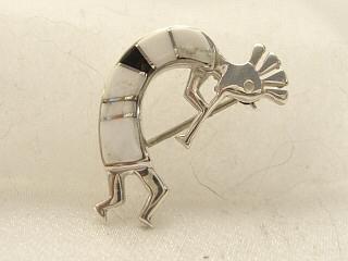 White Buffalo Turquoise and Jet inlaid between ribbons of Sterling Silver. Stunning Kokopelli Brooch. This Beautiful Stone is formed from the mineral Magnesite. It is mined near Elko Nevada. Created by Navajo Artist Calvin Begay. 