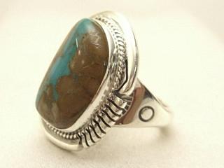 Genuine Boulder Turquoise set in Sterling Silver Ring. The cabachons are of Boulder Turquoise, you can see the veins of Turquoise running through the host rock. The Boulder Turquoise Mine is located in northeast Nevada. It was discovered in 1970 by a Shoshone sheep herder. Production is small due to the remote location and winter weather. Boulder Turquoise is valued for both it's beauty and rarity. Every stone is unique. Created by Navajo Artist John Nelson. Signed. 
