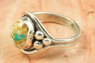 Genuine Boulder Turquoise set in Sterling Silver Ring. The cabachon is Boulder Turquoise, you can see the veins of Turquoise running through the host rock. The Boulder Turquoise Mine is located in northeast Nevada. It was discovered in 1970 by a Shoshone sheep herder. Production is small due to the remote location and winter weather. Boulder Turquoise is valued for both it's beauty and rarity. Every stone is unique. Created by Navajo Artist Bobby Piaso. Signed by the artist.