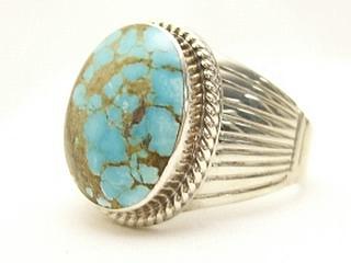 Genuine Number 8 Turquoise set in Sterling Silver Ring. The Number 8 mine is located in Eureka County Nevada. Since 1976 there has been no Number 8 Turquoise mined. There is however, an existing stock pile that Mr. Dowell Ward, the last owner of the Number 8 mine, had stocked away for later sorting. The Turquoise is a collector's item--because once the reserve is gone there will be no more material released onto the market. The Gold Mining Company owns the claim to the Number 8 mine and it has been swallowed up by the gold mining operations. This is some of the last Number 8 Turquoise to be had and will be a great addition to your collection. Created by Navajo Artist Larson Lee. Signed. 
