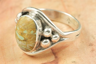 Genuine Boulder Turquoise set in Sterling Silver Ring. The cabachons are of Boulder Turquoise, you can see the veins of Turquoise running through the host rock. The Boulder Turquoise Mine is located in northeast Nevada. It was discovered in 1970 by a Shoshone sheep herder. Production is small due to the remote location and winter weather. Boulder Turquoise is valued for both it's beauty and rarity. Every stone is unique. Created by Navajo Artist Bobby Piaso. Signed by the artist.
