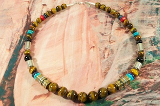 Genuine Assorted Gemstones Necklace. Featuring Genuine Turquoise, Malachite, Black Onyx and Coral. Sterling Silver Barrels, Beads and Clasp. Created by Navajo Artist Tommy Singer. Signed.
