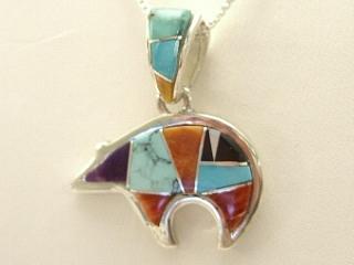 Genuine Turquoise, Spiny Oyster Shell, Blue Lapis and Black Jade inlaid between ribbons of Sterling Silver. Beautiful bear design with precision inlay on the bale and pendant. Free 18" Sterling Silver Chain with Purchase of Pendant. Created by Navajo Artist Calvin Begay. Signed.
