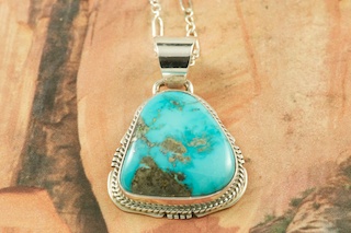 Genuine Castle Dome Turquoise set in Sterling Silver Pendant. Created by Navajo Artist Kathy Yazzie. Signed by the artist. The Castle Dome Turquoise Mine is located about 30 miles from the Sleeping Beauty Mine, near Globe, Arizona. The Castle Dome Mine has not been in operation since the early 1970s. Free 18 inch Sterling Silver Chain with purchase of pendant.
