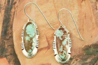 Genuine Number 8 Mine Turquoise Stones set in Sterling Silver French Wire Earrings. The Number 8 mine is located in Eureka County Nevada. Since 1976 there has been no Number 8 Turquoise mined. There is however, an existing stock pile that Mr. Dowell Ward, the last owner of the Number 8 mine, had stocked away for later sorting. The Turquoise is a collector's item--because once the reserve is gone there will be no more material released onto the market. The Gold Mining Company owns the claim to the Number 8 mine and it has been swallowed up by the gold mining operations. This is some of the last Number 8 Turquoise to be had and will be a great addition to your collection. Created by Navajo Artist Arkie Nelson. Signed by the artist.  
