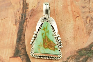 Genuine Pilot Mountain Turquoise set in Sterling Silver Pendant. Free 18 inch Sterling Silver Chain with purchase of pendant. The Pilot Mountain mine is located in Esmeralda County, Nevada. Created by Navajo Artist Justin Morris. Signed by the artist. Justin Morris incorporates meaning in his Sterling Silver Designs. The Sterling Silver Feather represents Life, the Circle of Life represents Balance and the Raindrops represent Abundance.