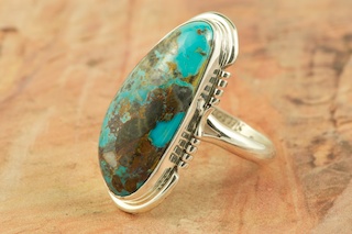 Genuine Sunnyside Turquoise set in Sterling Silver Ring. The matrix on this rare stone is outstanding. The Sunnyside mine is located in northern Nevada near the town of Tuscarora in the Tuscarora mountain range. The mine is no longer in operation as it has become part of a gold mining operation and a privately owned ranch. The Sunnyside mine was mined mostly in the 70's. You won't find much of this great turquoise around anymore except for old stashes. Created by Navajo Artist Arkie Nelson. Signed by the artist.  