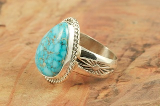 Genuine High Grade Kingman Web Turquoise set in Sterling Silver Ring. Created by Navajo Artist Tony Garcia. Signed by the artist. The Mineral Park Mine, in the Cerbat Mountains 14 miles northwest of Kingman, was first mined by Indians centuries before white man came to the area. It is one of the three sites of prehistoric mining localities in the state of Arizona. Mineral Park was the most extensively worked area by the Indians of the three. S.A. �Chuck� Colbaugh found a cache of stone hammers uncovered in ancient trenches and tunnels, when he had the turquoise mining concession in May of 1962. Ithaca Peak and Turquoise Mine (formally called Aztec Mountain or Aztec Peak) are the most famous of the peaks in the area containing turquoise.