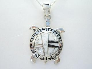Authentic Native American Jewelry. White Buffalo Turquoise and Jet inlaid between ribbons of Sterling Silver. Beautiful inlay work on the bale of this Turtle Pendant. This Beautiful Stone is formed from the mineral Magnesite. It is mined near Elko Nevada. Created by Navajo Artist Calvin Begay. Free 18 