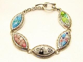 Millefiori Bracelet A multi color Millefiroi oval glass detail hand set in a nickel free sterling silver bracelet. Millefiori is a type of Murano glass that has been incorporated with various layers of colors to create beautiful flower-like patterns. Millefiori, which literally means �a thousand flowers�, is the denomination of a type of cylindrical, long glass rod which contains a specific pattern along its entire length, so that when cut into slices from one end, the particular pattern will be revealed. It is completely handmade of authentic Murano glass. This style of glass has been around since the Middle Ages and more recently, has been produced for fine jewelry.