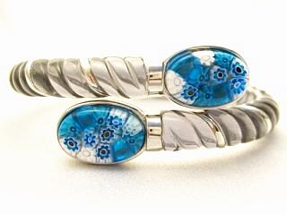 Millefiori Bracelet A rope design grey resin and silver bracelet, featuring 2 multi color oval millefiori glass details. This bracelet opens by a spring like hinge mechanism located at the bottom center of the bracelet. Millacreli combines the beautiful Millefiori patterns with the high-quality Murano art glass and colored resin. Millacreli uses 925 sterling silver with the durable, scratch-resistant colored resin and Millefiori glass to create unique and colorful jewelry.