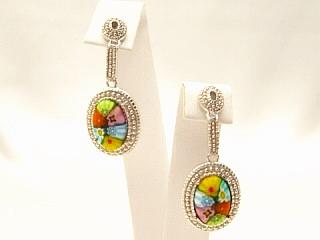 Millefiori Oval Earrings A multi color Millefiroi oval glass detail hand set in a nickel free sterling silver earring frame. Millefiori is a type of Murano glass that has been incorporated with various layers of colors to create beautiful flower-like patterns. Millefiori, which literally means �a thousand flowers�, is the denomination of a type of cylindrical, long glass rod which contains a specific pattern along its entire length, so that when cut into slices from one end, the particular pattern will be revealed. It is completely handmade of authentic Murano glass. This style of glass has been around since the Middle Ages and more recently, has been produced for fine jewelry.