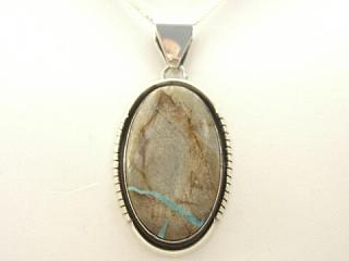Genuine Boulder Turquoise set in Sterling Silver Pendant.The cabachon is Boulder Turquoise,you can see the veins of Turquoise running through the host rock. Free 18" Sterling Silver Chain with Purchase of Pendant. Created by Navajo Artist Harry Spencer. Signed.